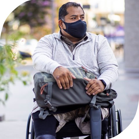 A Hispanic man wearing a mask and sitting in a wheelchair.